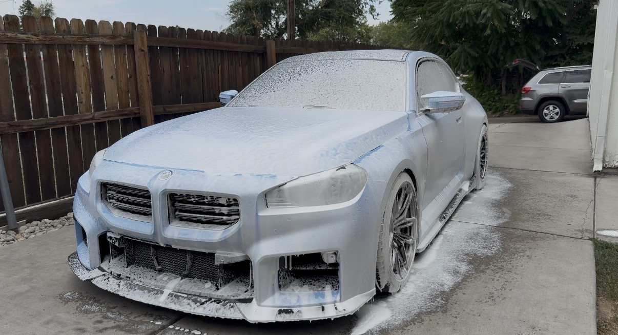 Silver BMW covered in thick foam bath prep wash